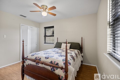 A bedroom with a four-poster bed and a ceiling fan.