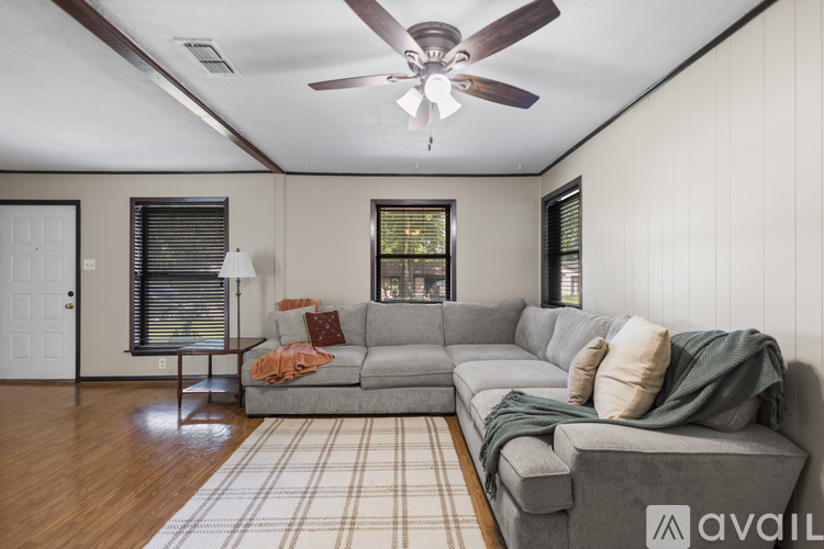 A living room with a grey couch and a ceiling fan.