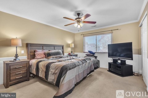 A bedroom with a bed, a television, and a ceiling fan.