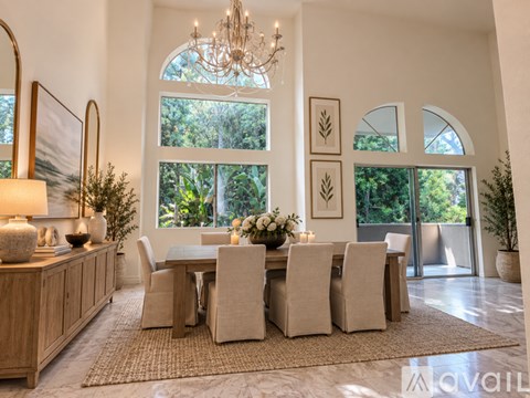 A dining room with a table set for six and a chandelier hanging from the ceiling.
