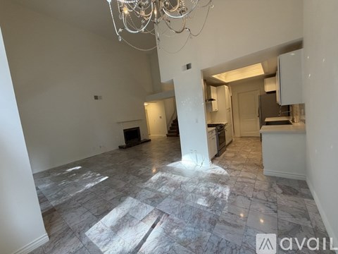 A spacious room with marble flooring and a chandelier.