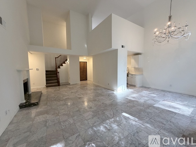 A spacious living room with marble flooring and a chandelier.