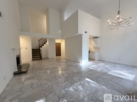 A spacious living room with marble flooring and a chandelier.