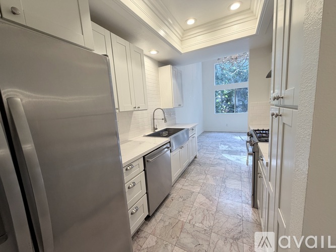 A kitchen with a refrigerator on the left and a sink in the middle.
