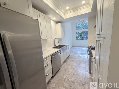 A kitchen with a refrigerator on the left and a sink in the middle.