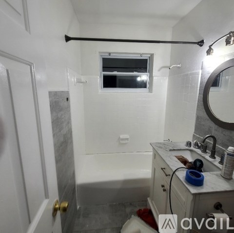 A bathroom with a white tub, sink, and a window.