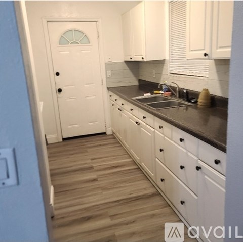 A kitchen with white cabinets and a white door.