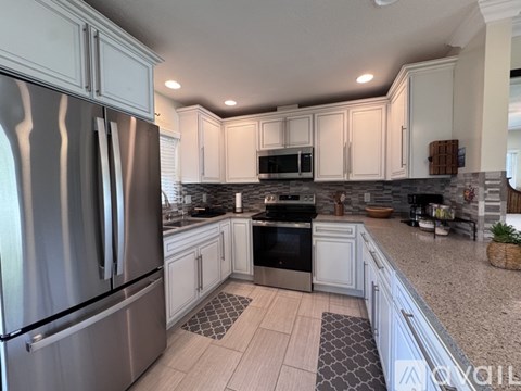 A modern kitchen with a stainless steel refrigerator and white cabinets.