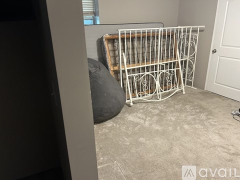 A white baby gate is leaning against a wall in a room with a grey carpet.