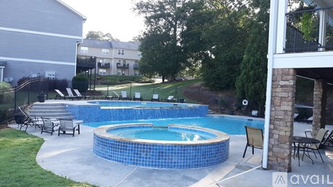 A blue tiled pool with a white fence and green lawn.