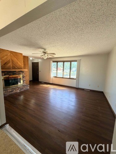 A room with a fireplace and wood flooring.
