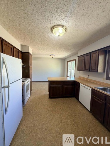 A kitchen with brown cabinets and a white refrigerator.