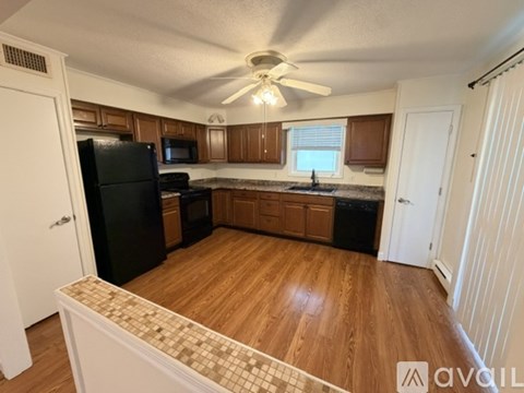 A kitchen with wooden cabinets and a black fridge.