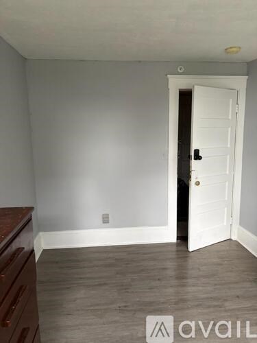 A room with a white door and wooden floor.
