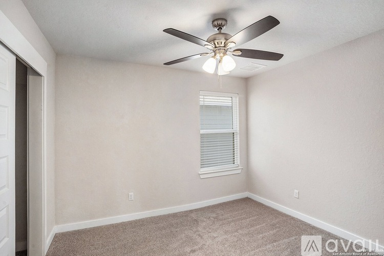 A room with a ceiling fan and a window with blinds.