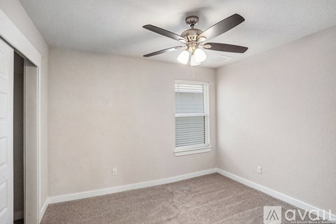 A room with a ceiling fan and a window with blinds.
