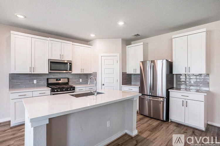 A kitchen with white cabinets and a stainless steel refrigerator.