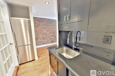 A kitchen with a stainless steel refrigerator and a brick wall in the background.