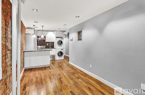 A kitchen with a brick wall and wooden floors.