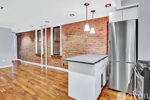 A kitchen with a brick wall and wooden floors.