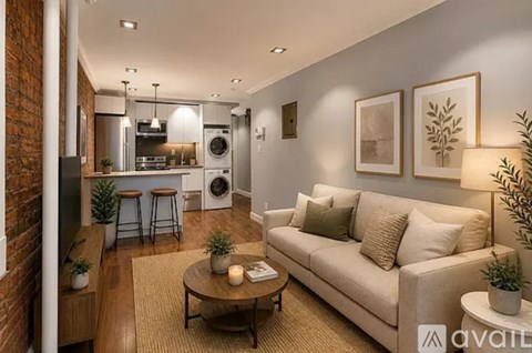 A modern living room with a brick wall and a kitchen in the background.