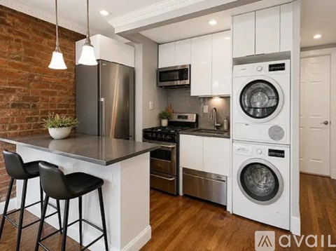 A modern kitchen with a brick wall and a white washing machine.