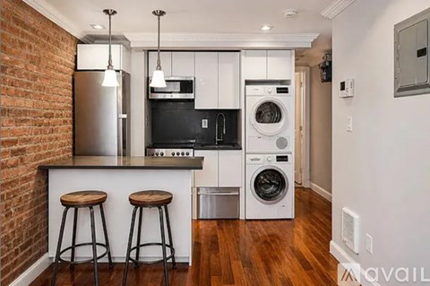 A kitchen with a brick wall and wooden floors.
