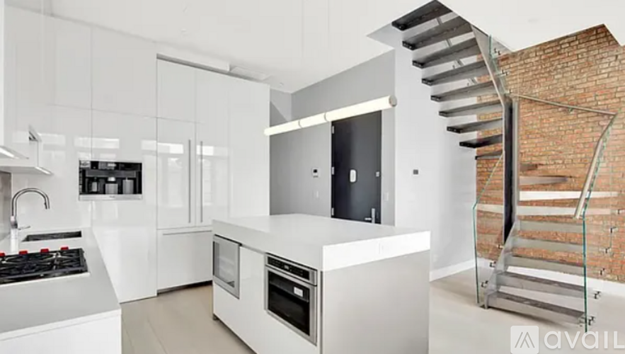 A modern kitchen with a brick wall and a staircase.