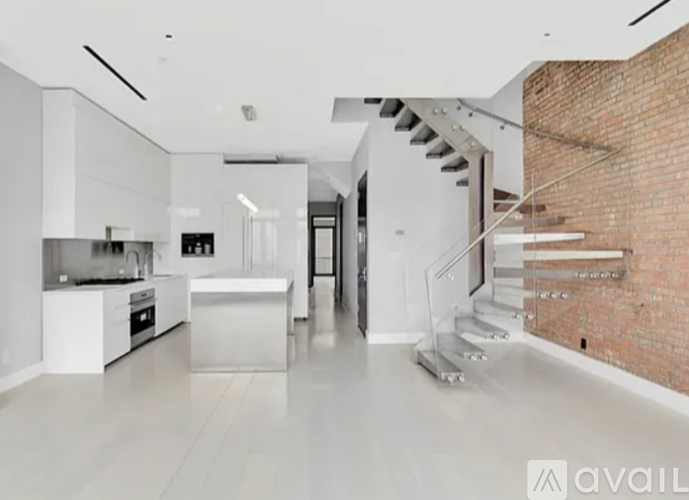 A modern kitchen with white cabinets and a brick wall.