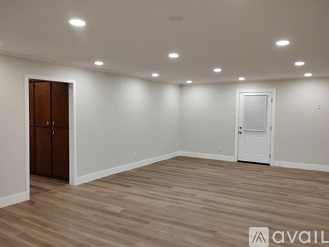 A room with wooden flooring and two doors, one of which is closed.
