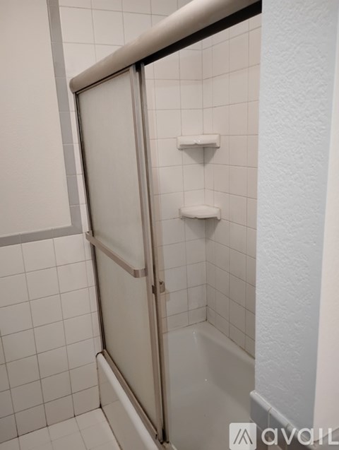 A white tiled bathroom with a shower door.