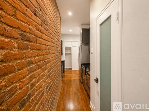 A hallway with a brick wall on the left and a white door on the right.