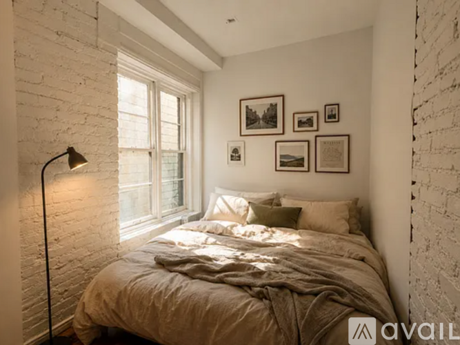 A bedroom with a bed, pillows, a lamp, and pictures on the wall.
