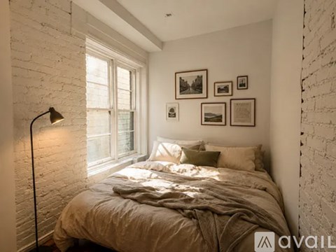 A bedroom with a bed, pillows, a lamp, and pictures on the wall.