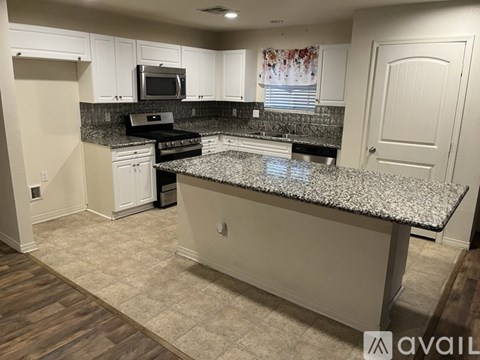 A kitchen with a granite countertop and white cabinets.