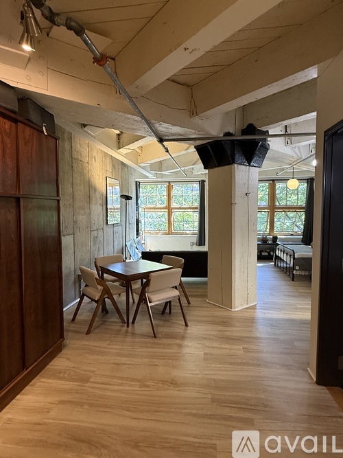 A room with a dining table and chairs in the foreground and a kitchen area in the background.