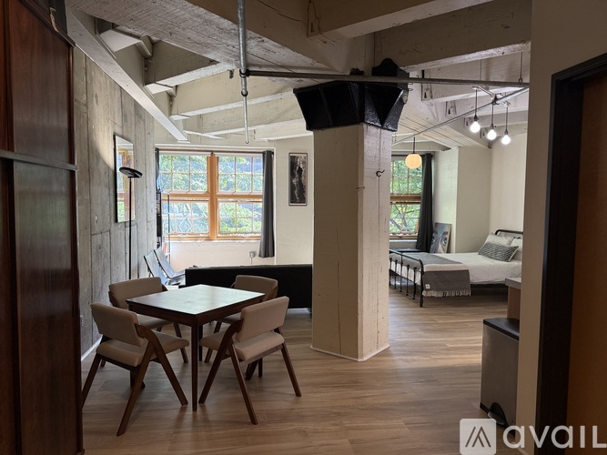 A room with a table and chairs in the foreground and a bed in the background.