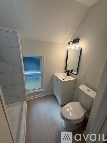 A bathroom with a toilet, sink, and mirror.
