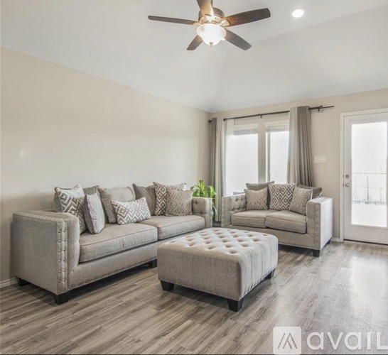 A living room with a grey sofa set and a ceiling fan.
