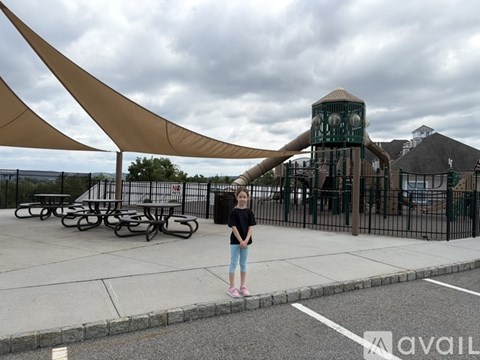 A girl stands in front of a playground with a large slide.