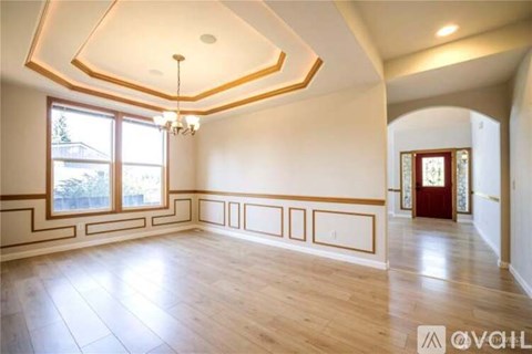A spacious room with wooden floors and a chandelier.