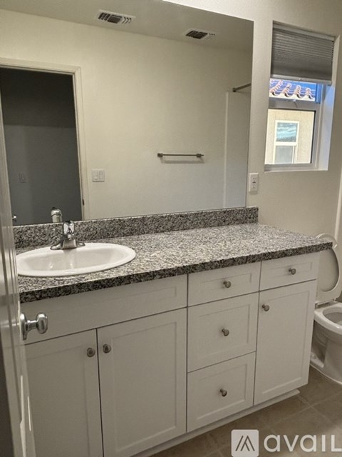 A bathroom with a granite countertop and white cabinets.
