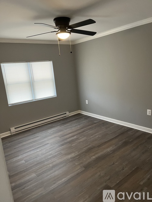 A room with a ceiling fan and a window with blinds.
