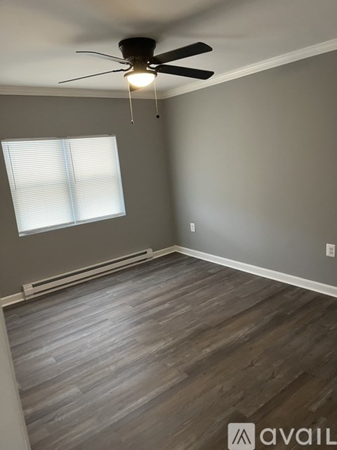 A room with a ceiling fan and a window with blinds.