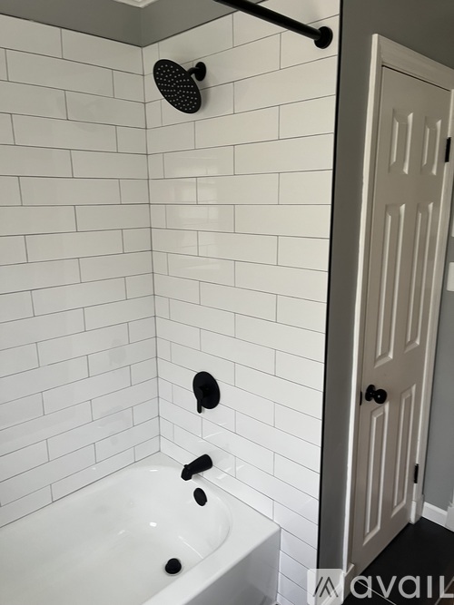 A white tiled bathroom with a white door.