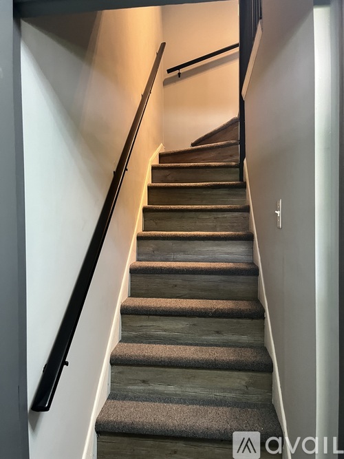 A staircase with a carpeted runner and a black handrail.