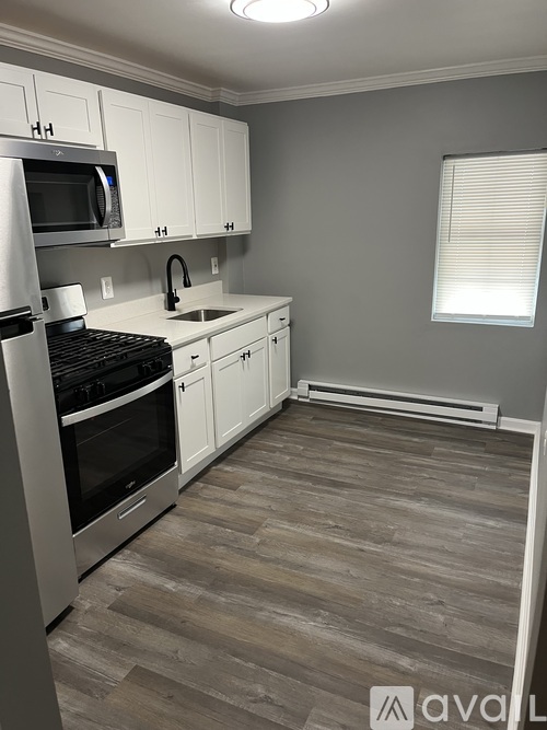 A kitchen with wooden floors and white cabinets.