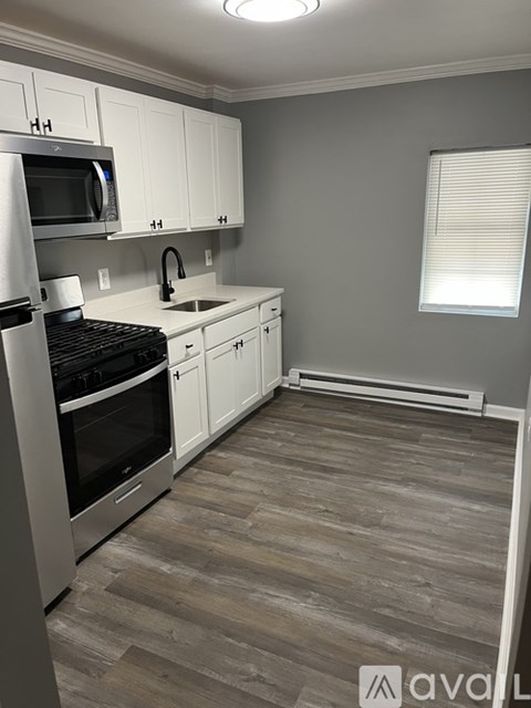 A kitchen with wooden floors and white cabinets.