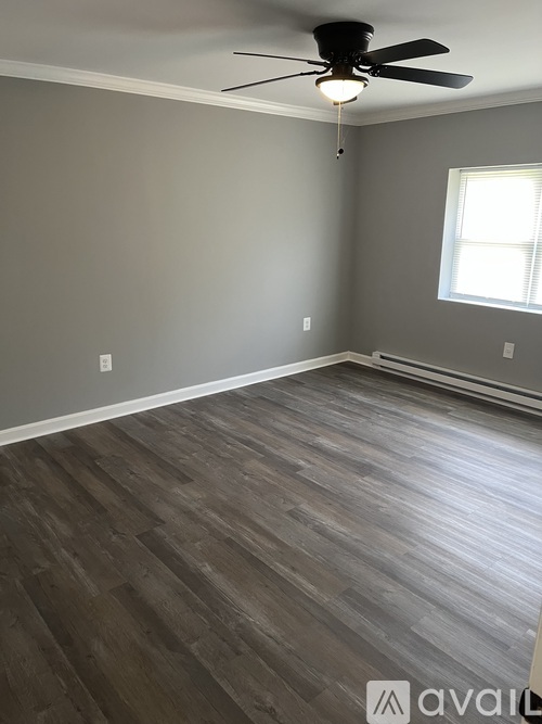 A room with a ceiling fan and wooden flooring.