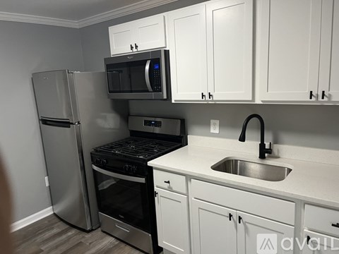 A kitchen with white cabinets and a stainless steel refrigerator.